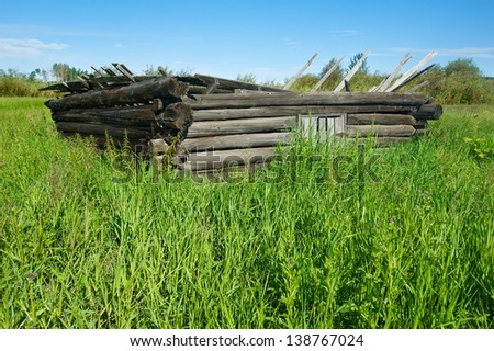 collapsed log cabin in grassy field