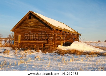 Old abandoned log cabin at sunrise in winter