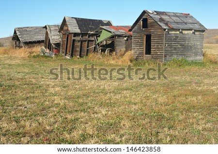 Old granaries on the edge of hayfield  in fall  Buildings In various stages of collapse