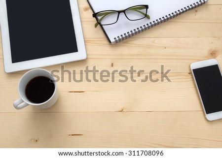 smartphone ,notepad ,glasses and notebook with a cup of coffee  on wood desktop