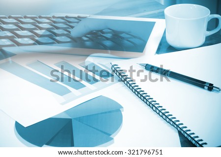 Modern business workplace with computer and digital tablet, mobile banking on a smartphone and some charts and graphs on a desktop.