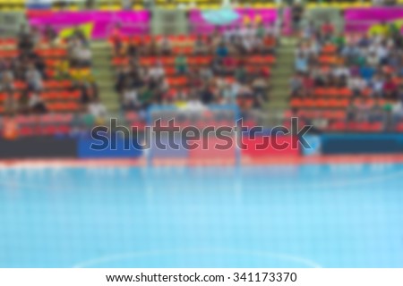 Blurred crowd of spectators in the indoor stadium with futsal match.