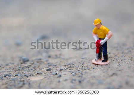 small figure of worker digging concrete.