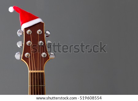 Red Christmas hat on guitar with grey background, Merry Christmas song