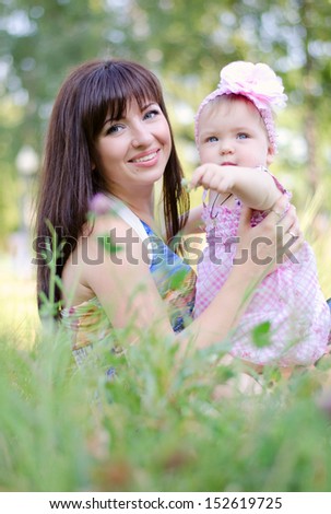 little girl standing on the grass near her mom and point a finger away