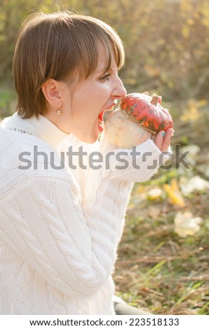 Hungry girl biting a pumpkin on Halloween