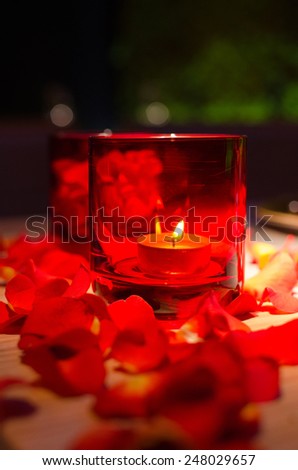 Romantic Valentine\'s Day decor of lighted candles and petals of red roses