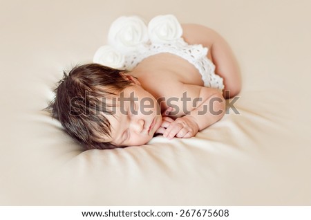 Portrait of a newborn girl sleeping on her stomach in a lace skirt with white roses