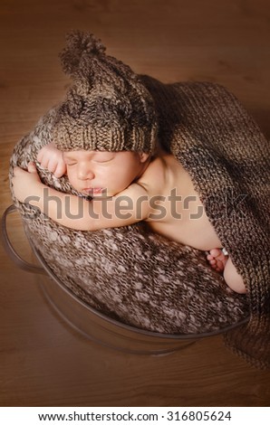 little sleeping baby in a brown knit cap under a brown blanket