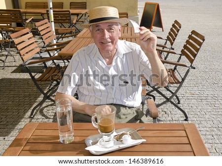 Senior man would like to pay for his coffee in the cafe.