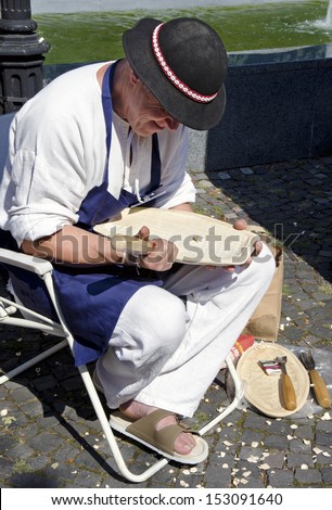 BRATISLAVA, SLOVAKIA - AUGUST 31, 2013 - The woodcarver in traditional outfit is processing the wood during Festival Craftsmen Days August 31th 2013 in Bratislava.