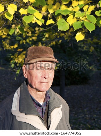 The senior man looking to the sun in sunny autumn day. Portrait.