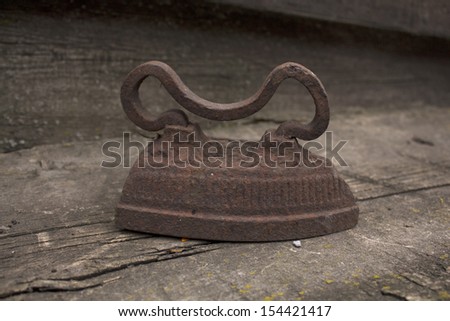 Old iron iron on the wooden background. Photo.