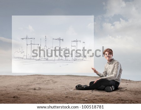 Young businessman holding the project for the construction of a city