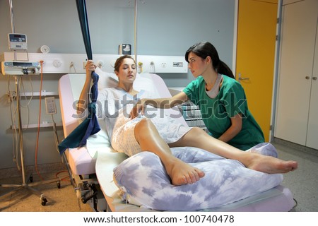Pregnant woman assisted by a nurse in a delivery room