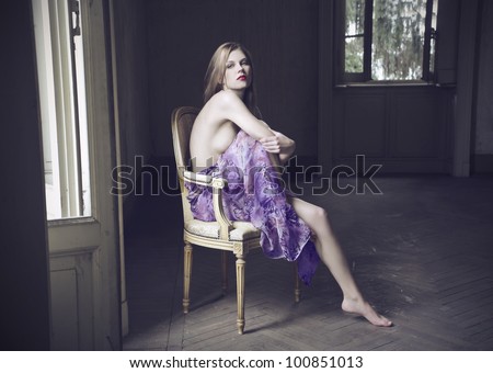 Beautiful woman sitting on an antique chair in an empty room
