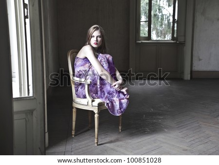 Beautiful woman sitting on an old chair in an empty room