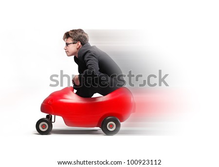 Young businessman driving fast on a toy car