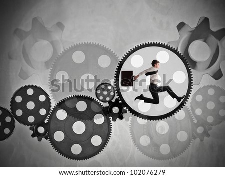 Young businessman running in a gear of a mechanism