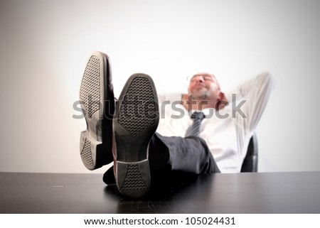 Businessman relaxing on a chair at the office with his feet on the table