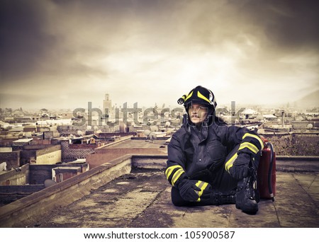 Fireman sitting on the rooftop of a skyscraper over a big city