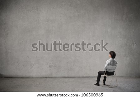 Businessman sitting on a chair in front of a wall