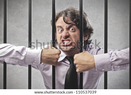 Angry businessman trying to bend cell bars