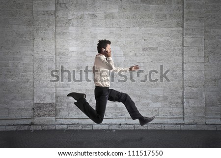 Young businessman running fast while talking on the mobile phone