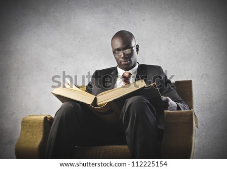 African man reading a book on an armchair