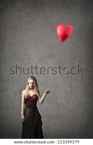 Elegant blonde woman holding a red shaped balloon heart