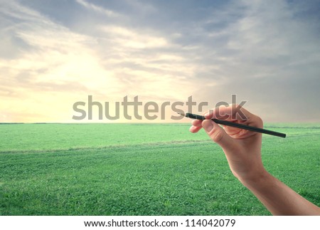 Hand with a pencil on a landscape