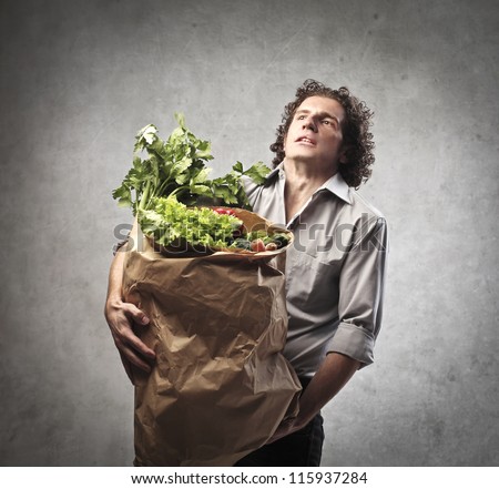 Man holding a very heavy bag full of vegetables