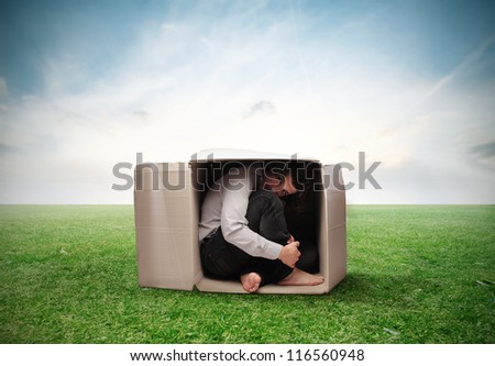 Man crouched in a box on a large grace field