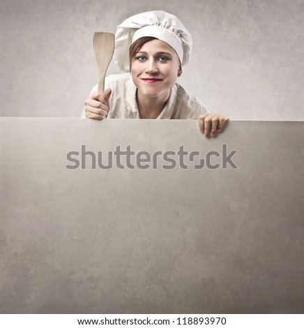 Woman, dressed as a cook, showing her wooden spoon