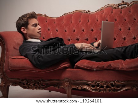 Young businessman using a laptop computer on an antique sofa
