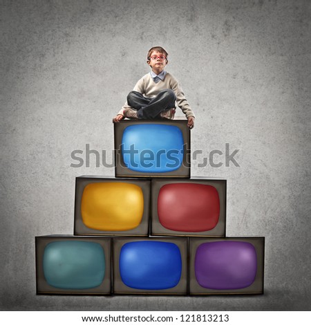 Child sitting on many televisions