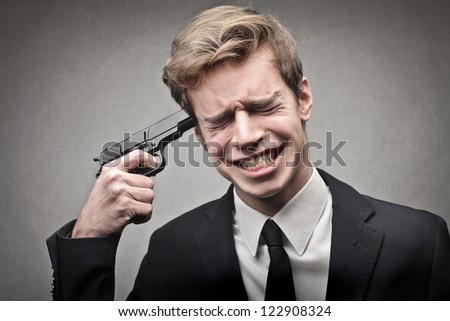 Young businessman pointing a gun to his head