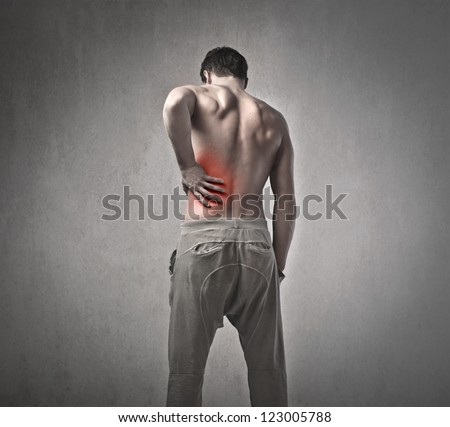 Shirtless man touching his back for the pain