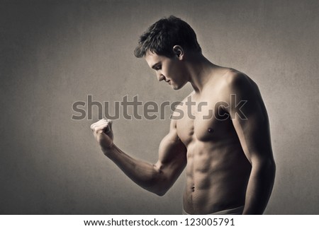 Muscular man flexes his right arm muscle