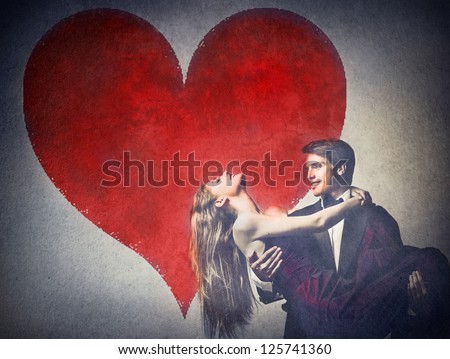 Two elegant young lovers dancing with a big heart drawn on a wall in the background