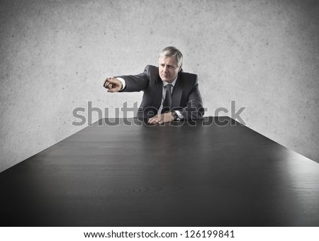 Old businessman at the head of a long black table indicates someone with aggression