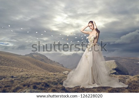 Elegant woman losing some petals in a wasteland