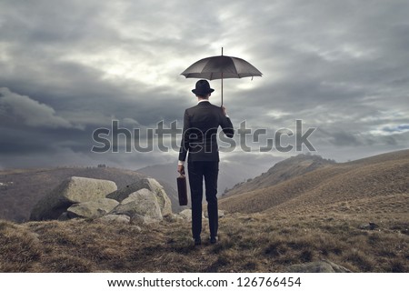 elegant man with umbrella shot from behind in the mountains