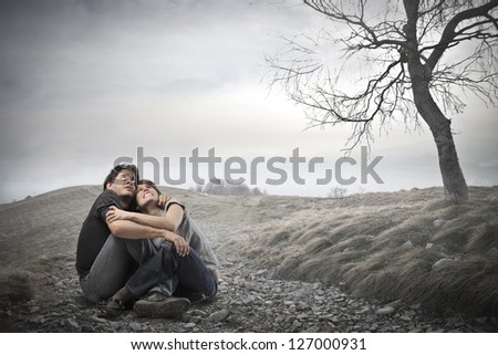 frightened young couple sitting in the middle of nature embrace