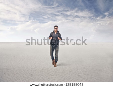 tourist with backpack and sunglasses walking in the desert