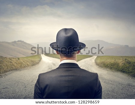 businessman with hat in front of two roads