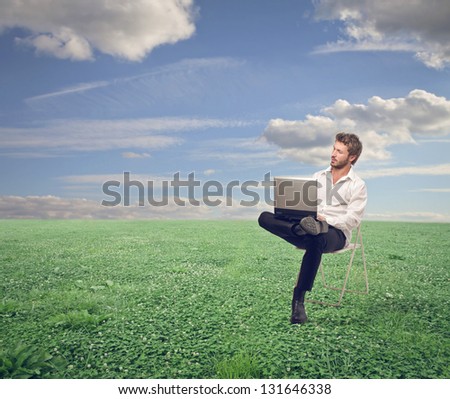 young businessman sitting on the chair with laptop in the country