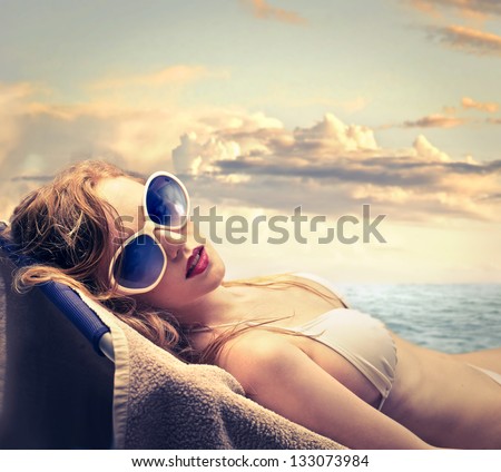 Blonde Woman In Bikini Sunbathing On The Beach