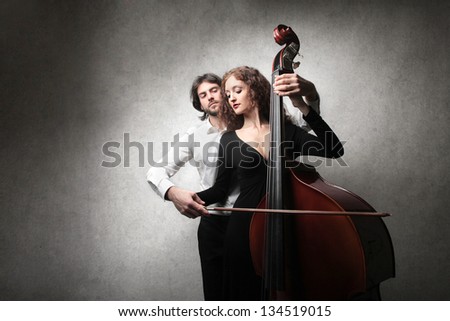 young man teaches playing contrabass to a beautiful woman