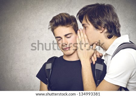 young boy talking to his friend in the ear